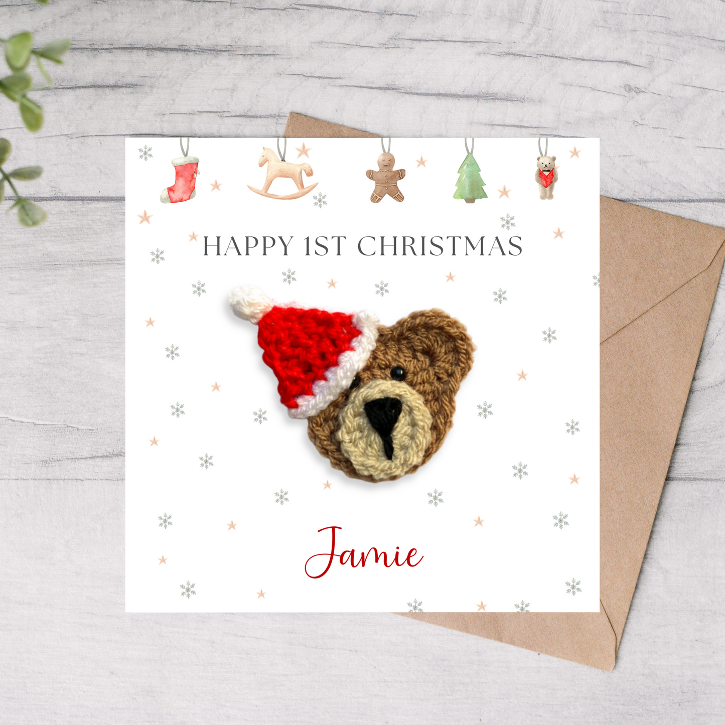 Crocheted teddy bear with a Santa hat on a Christmas card, featuring the text 'Happy 1st Christmas Jamie'.