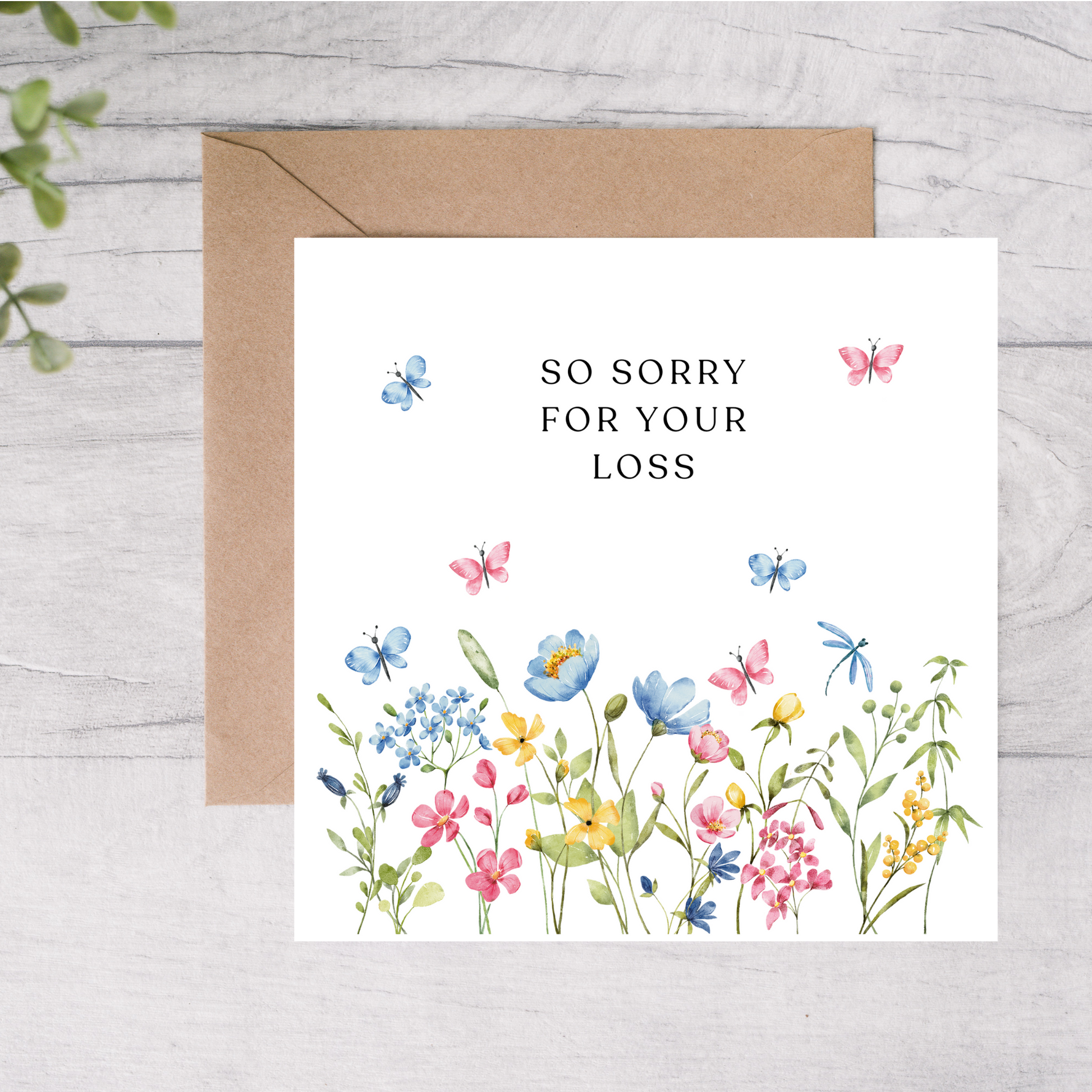 Greeting card with floral design and 'So sorry for your loss' text on a wooden surface.