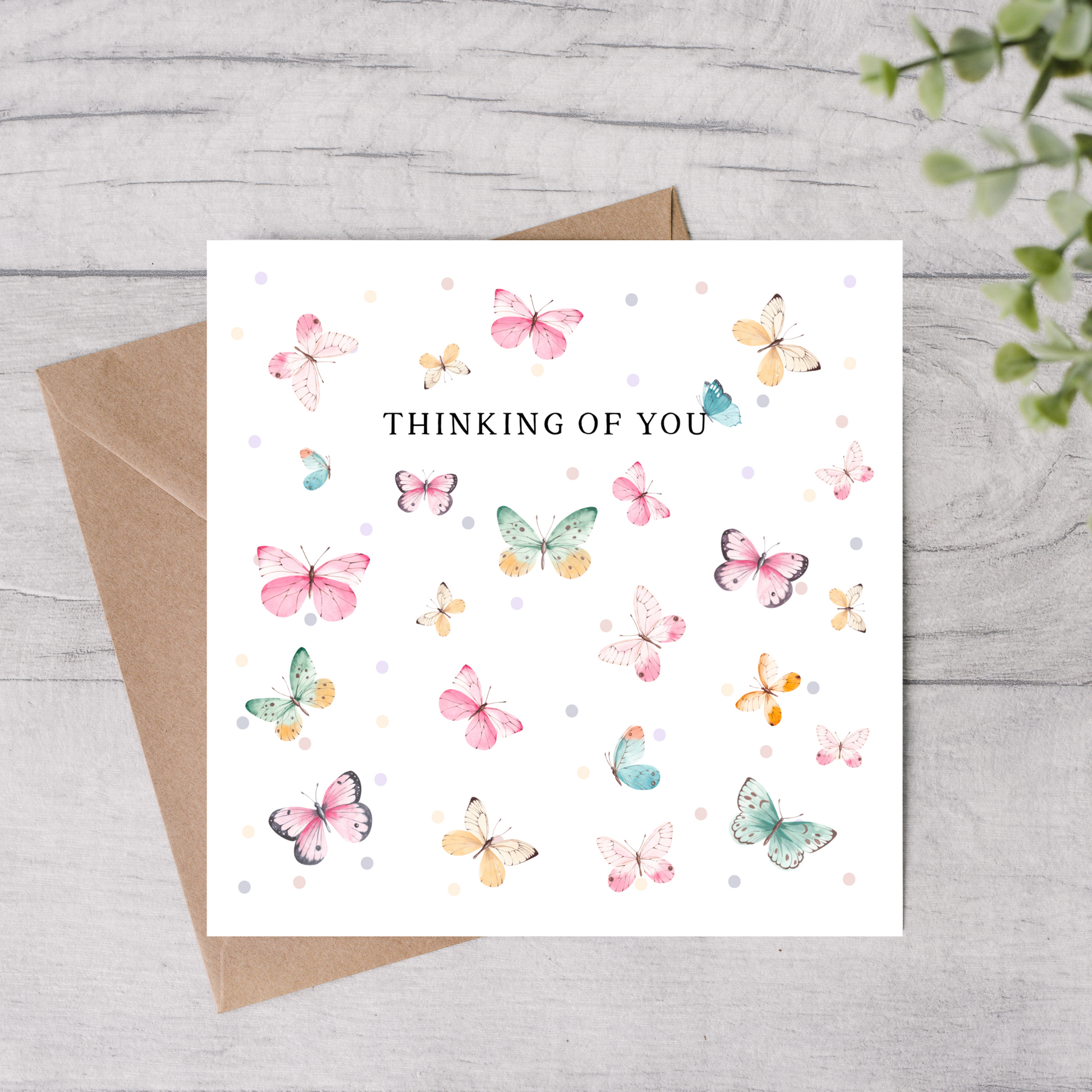 Greeting card with colorful butterflies and 'Thinking of You' text on a wooden surface.