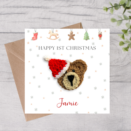 Christmas card with a crocheted bear wearing a Santa hat, on a wooden surface.